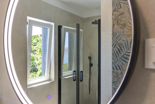 a bathroom mirror with a shower and a window at Apartmani Olimp2 in Sveti Juraj