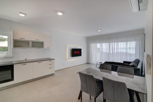 a kitchen and living room with a table and chairs at Apartmani Olimp2 in Sveti Juraj
