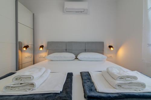 a bedroom with a white bed with towels on it at Apartmani Olimp2 in Sveti Juraj