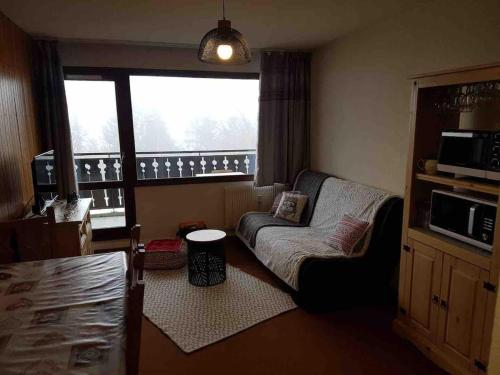 a living room with a couch and a large window at Studio cabine 5 couchages - Station du Collet d'Allevard in Allevard