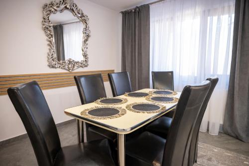 a dining room table with black chairs and a mirror at Aly&Emy 2 in Caransebeş