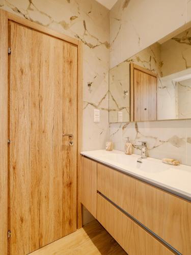 a bathroom with a sink and a wooden door at Terra Residence in Ágios Rókkos