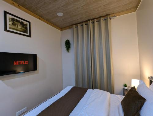 a bedroom with a bed and a tv on the wall at The Mall Ethos - On Mall Road - Kitchen - Sleeps 4 in Shimla