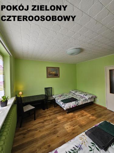 two beds in a room with green walls and wooden floors at Nocleg u garncarza in Kamienica Królewska