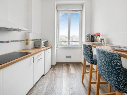 une cuisine avec des placards blancs et un comptoir avec une fenêtre dans l'établissement Séjour calme au cœur de Brest, vue sur la rade, à Brest