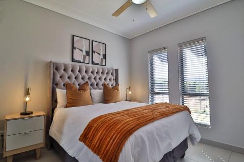 Un dormitorio con una cama grande y dos ventanas. en Lethukukhanya Luxury Apartment, en Nelspruit