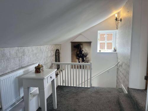 a white room with a staircase and a table at Jasmine Cottage in Burgh le Marsh