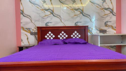 a bedroom with a purple bed with a wall at Yellow Bliss Homestay in Coimbatore