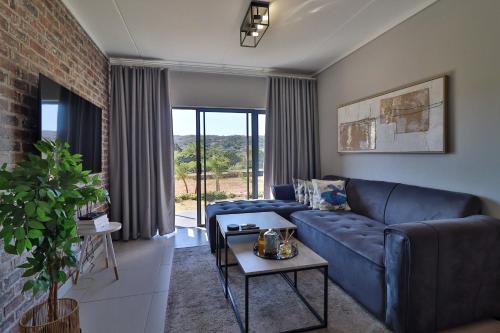 Una sala de estar con un sofá azul y una mesa. en Lethukukhanya Luxury Apartment, en Nelspruit