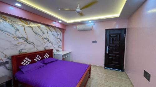 a bedroom with a purple bed and a wall at Yellow Bliss Homestay in Coimbatore
