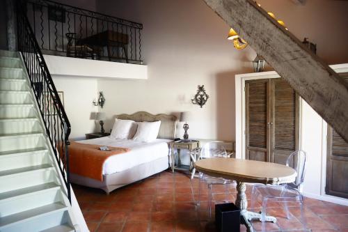a bedroom with a bed and a table and a staircase at Le Domaine Du Colombier in Malataverne