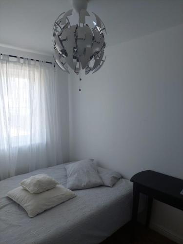 a white bedroom with a bed with a chandelier at SaFaRi 19 