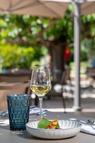 a glass of wine and a plate of food on a table at Le Domaine Du Colombier in Malataverne