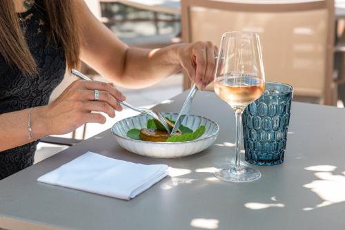 a woman sitting at a table with a glass of wine at Le Domaine Du Colombier in Malataverne