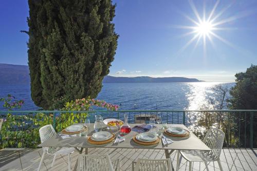 a table with plates of food on a balcony with the ocean at Villa Vinessa in Toscolano Maderno