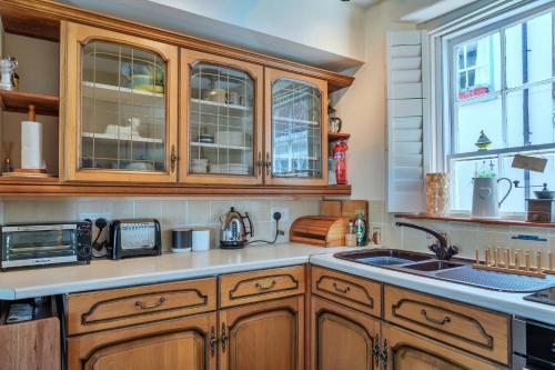 a kitchen with wooden cabinets and a sink at Finest Retreats - April Cottage in Cawsand