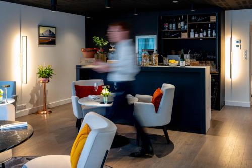 a person walking past a bar in a restaurant at Le Domaine Du Colombier in Malataverne
