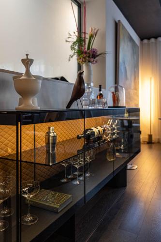 a glass shelf with wine glasses and vases on it at Le Domaine Du Colombier in Malataverne