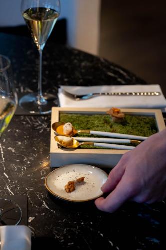 a person holding a plate of food and a glass of wine at Le Domaine Du Colombier in Malataverne