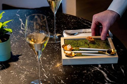 a person reaching for a plate of food and a glass of wine at Le Domaine Du Colombier in Malataverne
