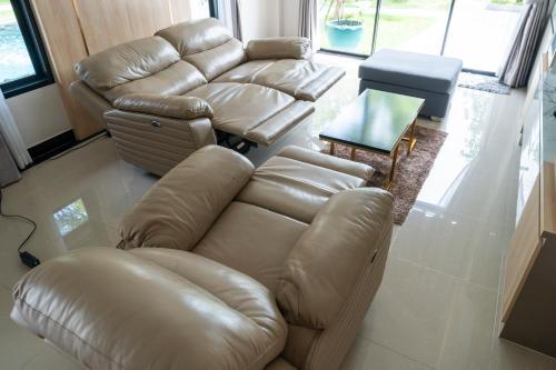 a living room with a leather couch and a table at BRAND-NEW! The Private PoolVilla /4BR byน้องมังคุด in Nong Prue