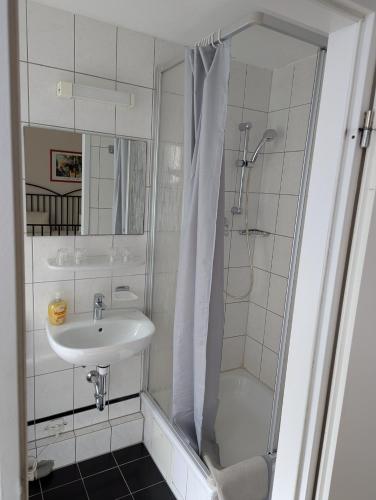 a white bathroom with a sink and a shower at Hotel Pension Waizenegger am Kurfürstendamm in Berlin