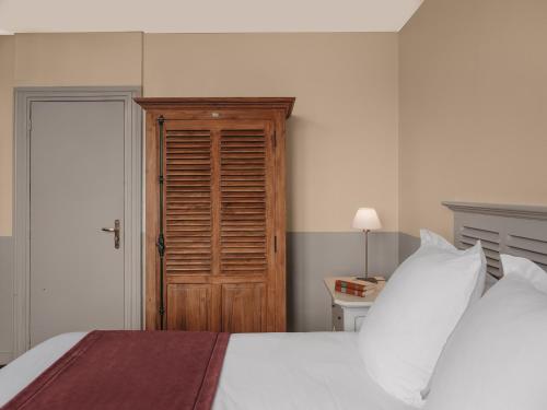 a bedroom with a white bed and a wooden door at Le Grand Large, Belle-Ile-En-Mer in Bangor