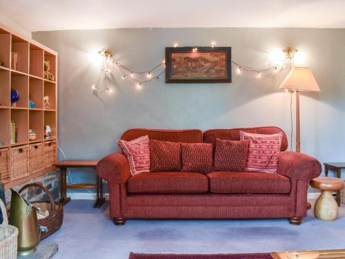 a living room with a red couch with pink pillows at The Cottage in Blakeney