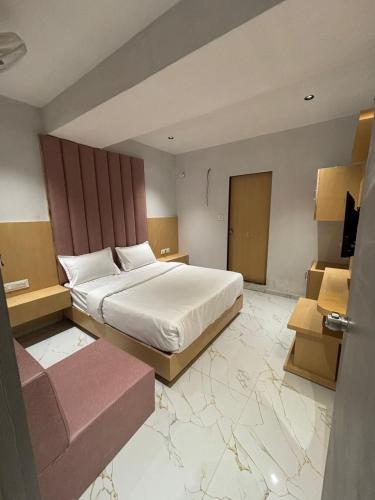 アーメダバードにあるHotel Pristineの大きな白いベッドとソファのある寝室