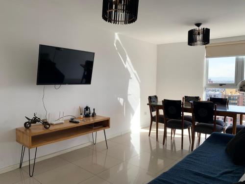 a living room with a table and a tv on the wall at ALOHA Güemes Premium, 2 dorm con Vista a las Sierras in Córdoba