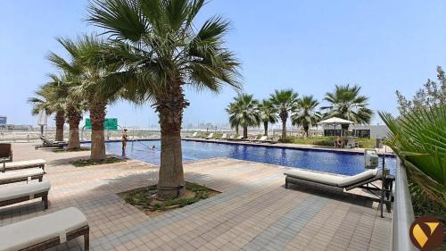 a swimming pool with palm trees and benches in a resort at Vogue Vacation Homes, Damac Hills Golf Gate near First Avenue Mall, Two Bedroom Apartment with Balcony and Vibrant Community View, Access to all Amenities in Dubai