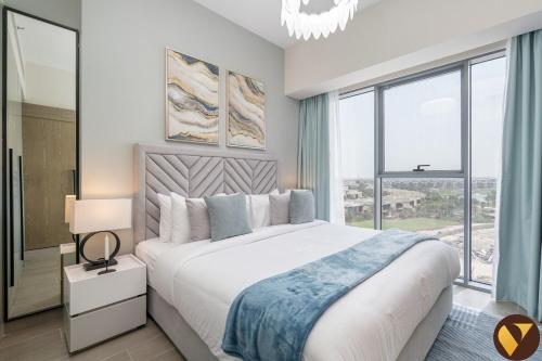 a bedroom with a large bed with a large window at Vogue Vacation Homes, Damac Hills Golf Gate near First Avenue Mall, Two Bedroom Apartment with Balcony and Vibrant Community View, Access to all Amenities in Dubai