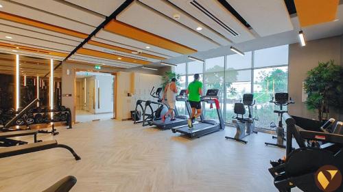 two people exercising in a gym with cardio equipment at Vogue Vacation Homes, Damac Hills Golf Gate near First Avenue Mall, Two Bedroom Apartment with Balcony and Vibrant Community View, Access to all Amenities in Dubai