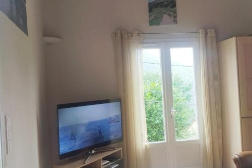 a flat screen tv in a room with a window at Maison de Martine & Christian in Eaux-Bonnes