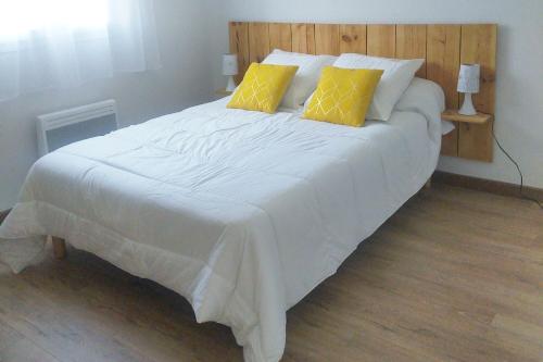 a large white bed with two yellow pillows on it at Maison de Martine & Christian in Eaux-Bonnes