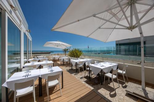 a restaurant with tables and white umbrellas on a deck at Nautilus Family Hotel in Pesaro