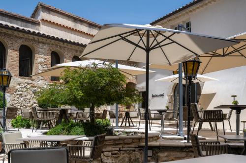 an outdoor patio with tables and chairs and an umbrella at Le Domaine Du Colombier in Malataverne