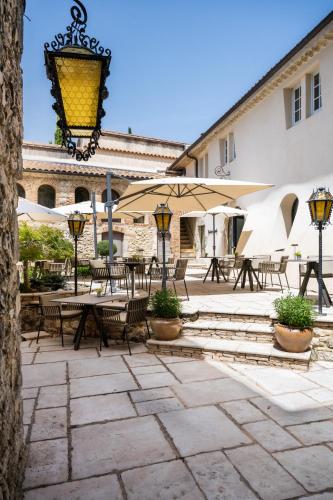 a patio with tables and chairs and umbrellas at Le Domaine Du Colombier in Malataverne