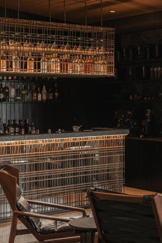 a bar with two chairs and a shelf with glasses at Silverback Lodge in Buhoma
