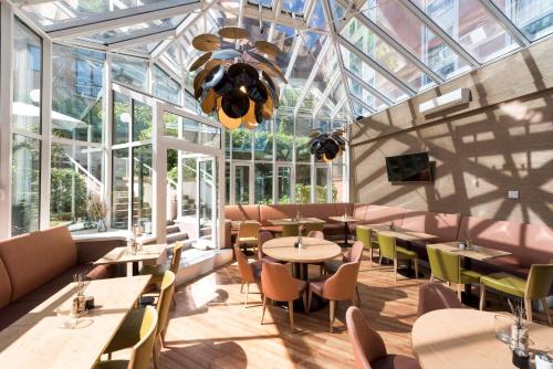 a restaurant with tables and chairs and windows at Scandic Berlin Kurfürstendamm in Berlin