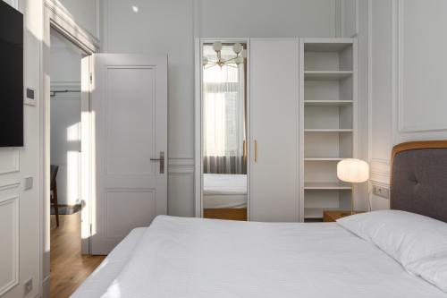 a bedroom with a white bed and a mirror at Roze Center Apartments in Liepāja