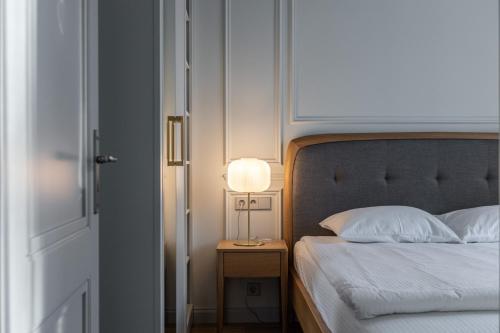 a bedroom with a bed and a lamp on a night stand at Roze Center Apartments in Liepāja
