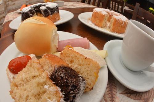 Una mesa con platos de pasteles y una taza de café. en FLAT HShotelaria, en Florianópolis
