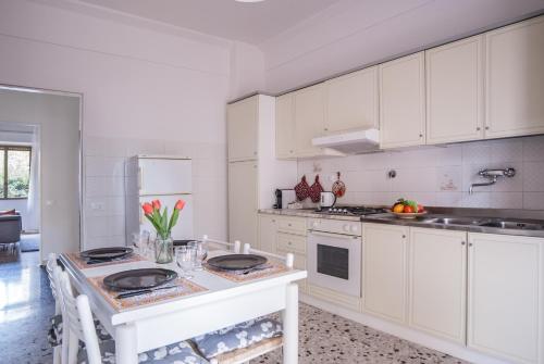 a white kitchen with white cabinets and a table at Scandicci Flat - 15 mins from Florence in Scandicci