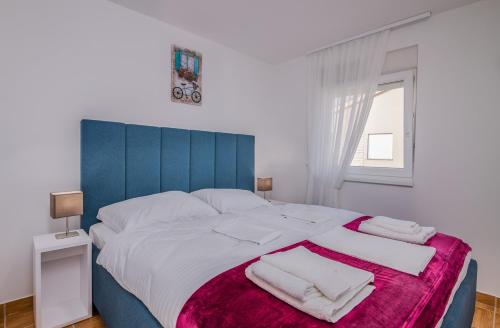 a bedroom with a large bed with a blue headboard at Apartment TRIES 5 with heated pool and sea view in Klimno