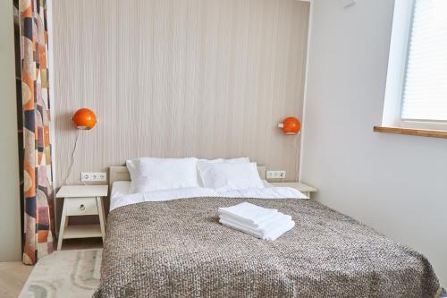 a bedroom with a bed with white sheets and orange lamps at Aia kodu in Haapsalu