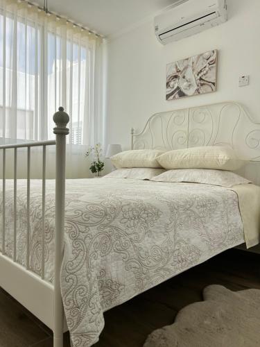 a white bedroom with a bed with a white bedspread at Sunlit Serenity in Paphos in Paphos