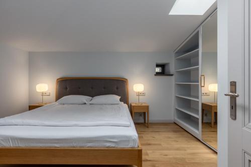a bedroom with a bed and two lamps on two tables at Roze Center Apartments in Liepāja