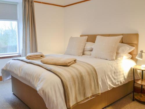 a bedroom with a large bed with white sheets and pillows at Woodside Farmhouse in Blairgowrie