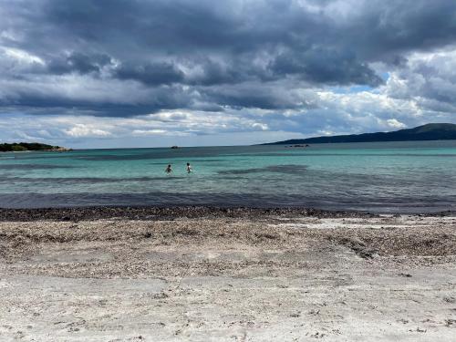two people are in the water on a beach at B&b La Casa Nel Vento in Torpè